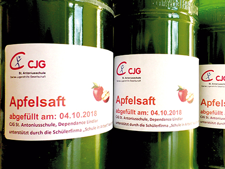 Grüne Flaschen des selbst hergestellten Apfelsaftes mit eigenem Etikett stehen in einer Reihe.